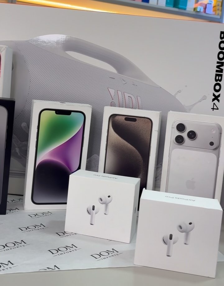 Caixas de iPhone, AirPods Pro e JBL Boombox sobre papel de seda da Dom Imports, com a prateleira de skincare ao fundo
